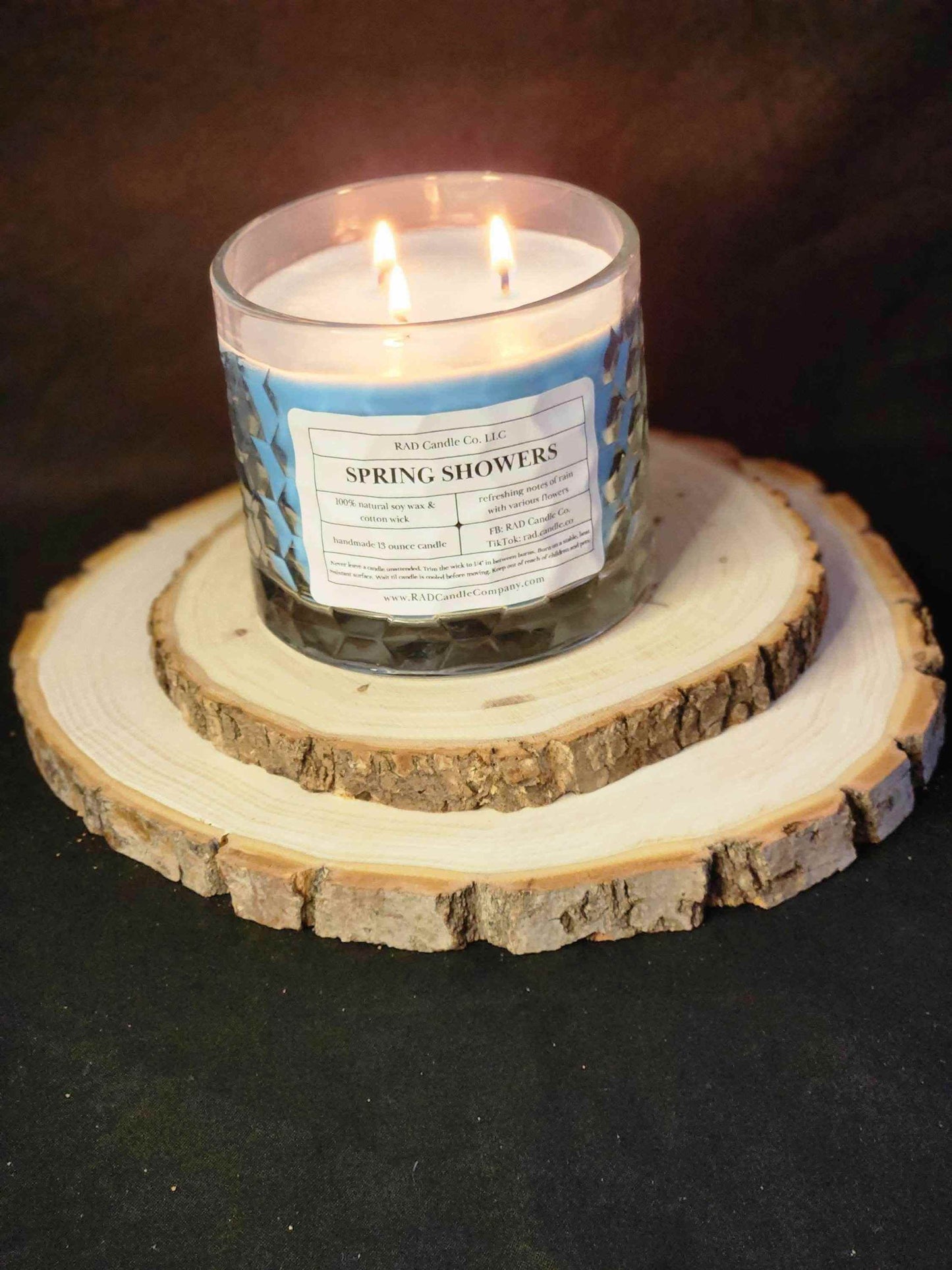 Spring Showers soy candle on a rustic wooden stand, featuring a fresh rainwater scent and calming jasmine notes.