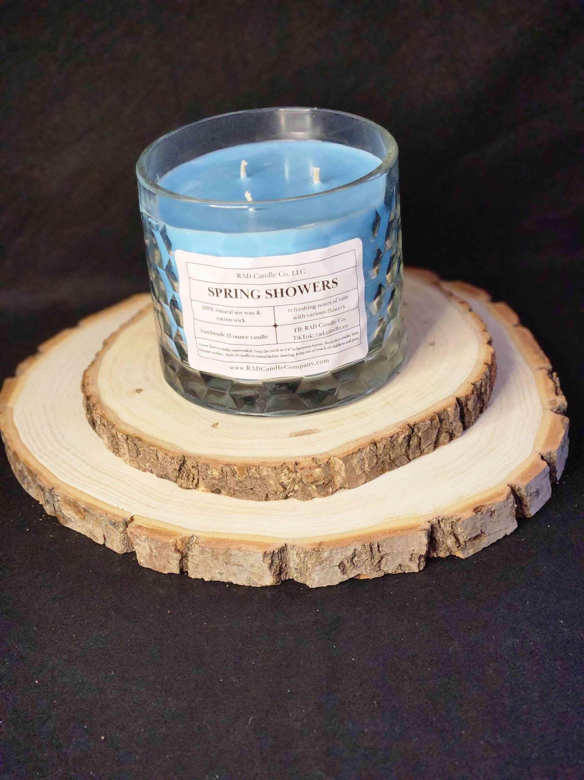 Spring Showers soy candle placed on wooden coasters, emitting a calming blue aroma for home decor.