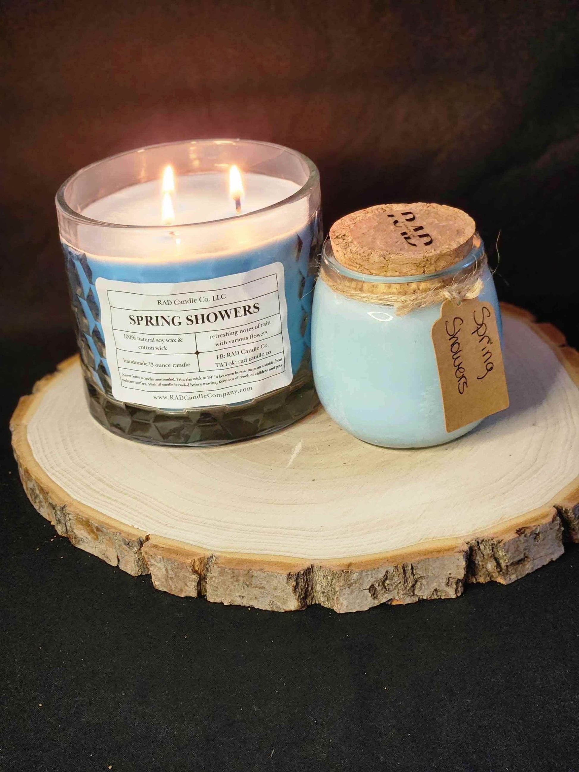 Spring Showers soy candle with two wicks and a small jar candle on a wooden slice, creating a calming ambiance.
