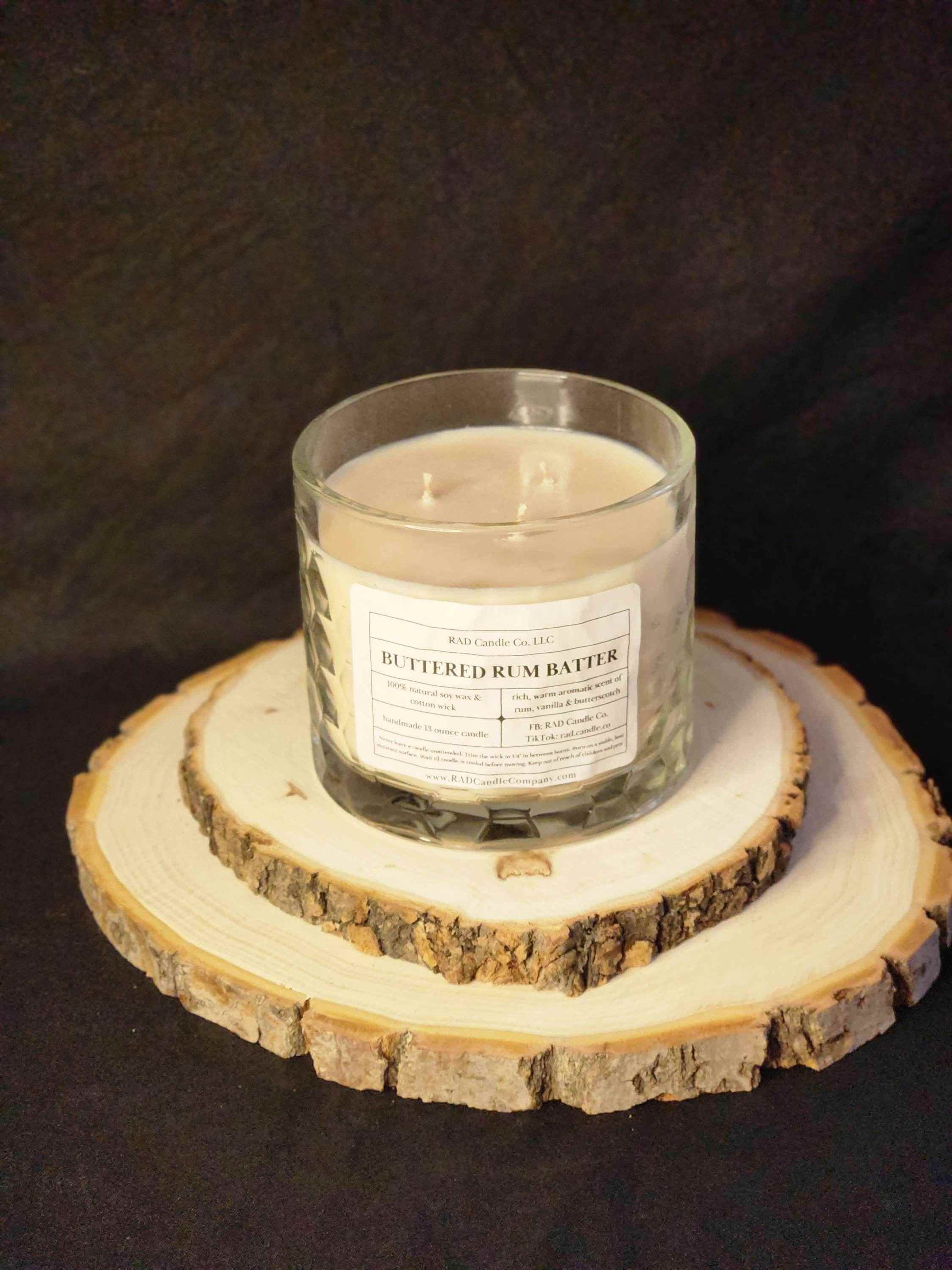 Buttered Rum Scented Soy Candle on a wooden slice, evoking cozy winter vibes with warm vanilla and brown sugar aroma.
